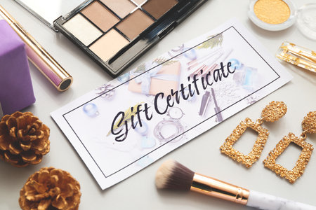 Gift certificate, decorative cosmetics and female accessories on light backgroundの写真素材
