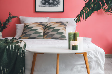 Burning candles on table in bedroom