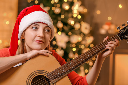 Mature woman playing guitar at home on Christmas eveの写真素材