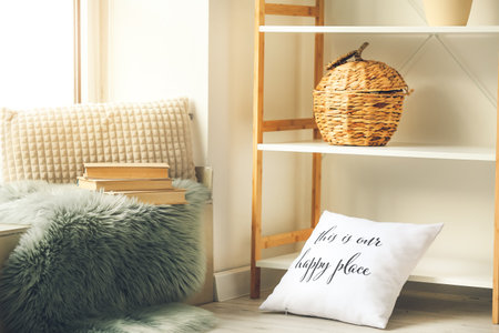 Old books with plaid and pillow on window sill in interior of room