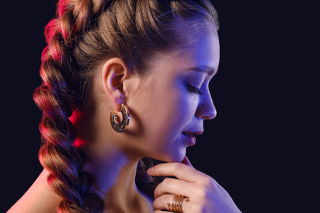 Beautiful young woman with braided hair on dark backgroundの写真素材