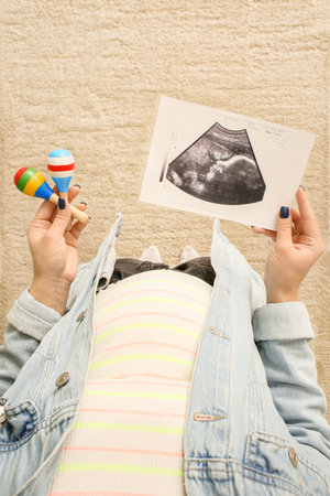 Pregnant woman with rattles and sonogram image at home, closeupの写真素材