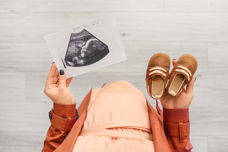 Pregnant woman with baby booties and sonogram image at home, closeupの写真素材