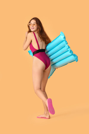 Beautiful young woman with inflatable mattress on color backgroundの写真素材
