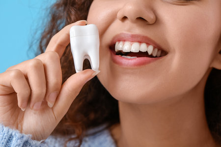 Beautiful young woman with model of tooth on color background, closeupの写真素材