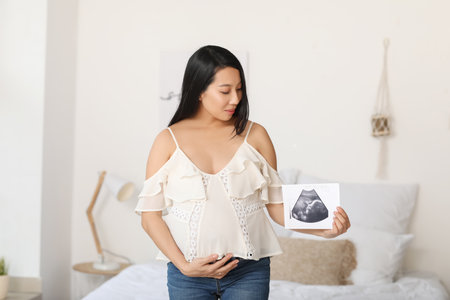 Pregnant Asian woman with sonogram image at home