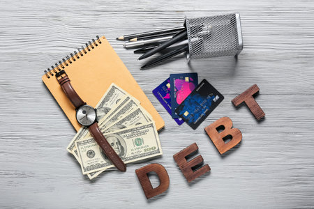 Money with credit cards and word DEBT on wooden backgroundの写真素材