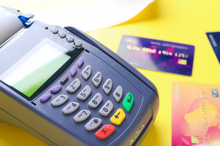 Payment terminal with credit cards on color background, closeup