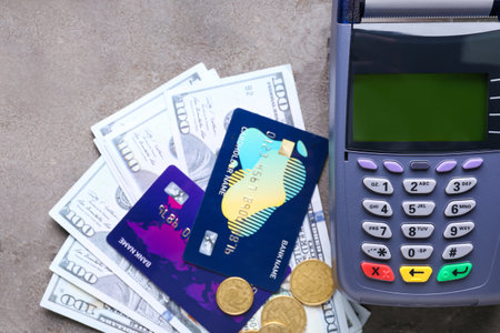 Payment terminal with credit cards and money on grunge background, closeup