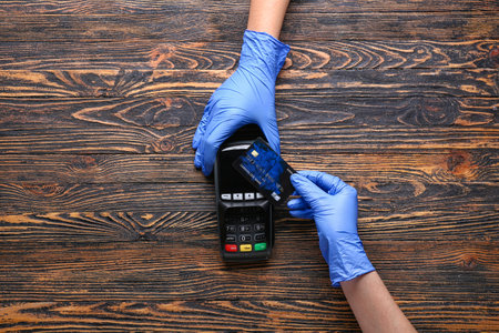 Female hands with credit card and payment terminal on wooden backgroundの写真素材