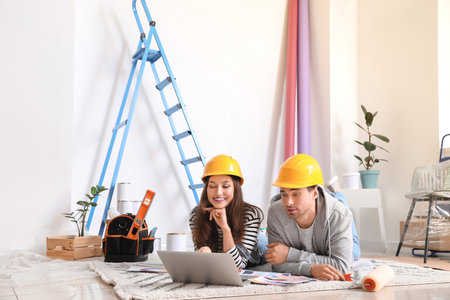 Happy young couple with palette samples and laptop planning repair in their new houseの写真素材