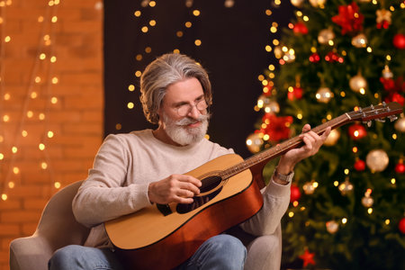 Senior man playing guitar at home on Christmas eveの写真素材