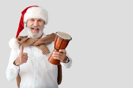 Senior man in Santa hat and with drum on gray backgroundの写真素材