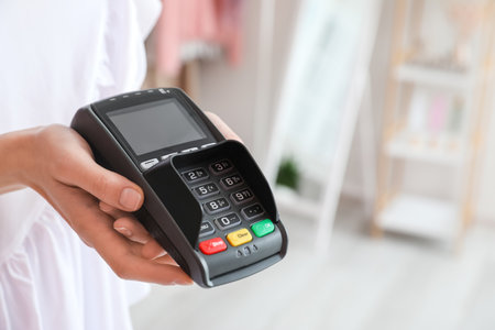 Seller with payment terminal in modern shop, closeup