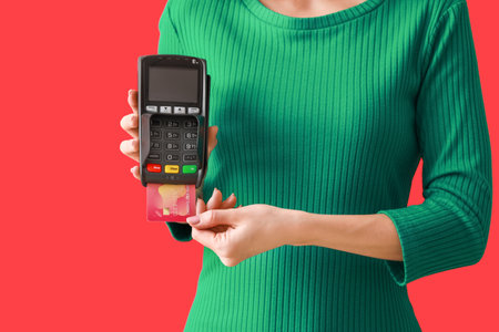 Young woman with payment terminal and credit card on color background, closeupの写真素材