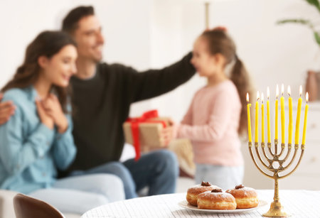 Menorah and donuts on table of happy family celebrating Hannukah at homeの写真素材