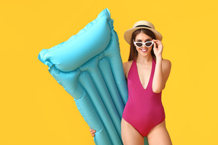 Beautiful young woman with inflatable mattress on color backgroundの写真素材