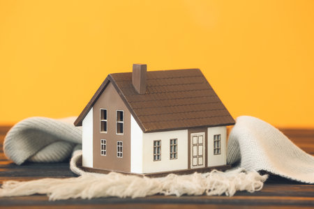 Figure of house and warm scarf on table. Concept of heating seasonの写真素材
