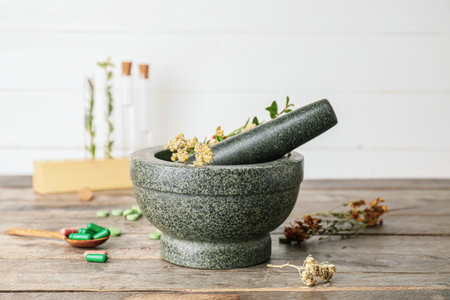 Stone mortar with herbs and pills on wooden table