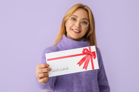 Mature woman with gift card on color backgroundの写真素材