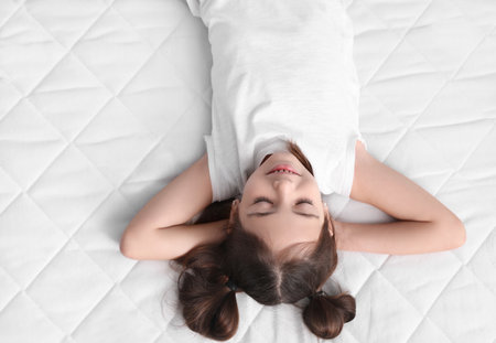 little girl sleeping on comfortable mattressの写真素材