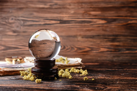 Crystal ball of fortune teller, spell book, cards and dry herbs on wooden tableの写真素材