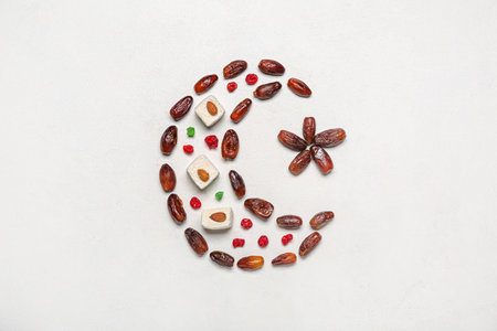 Crescent with star made of treats for Ramadan on gray background