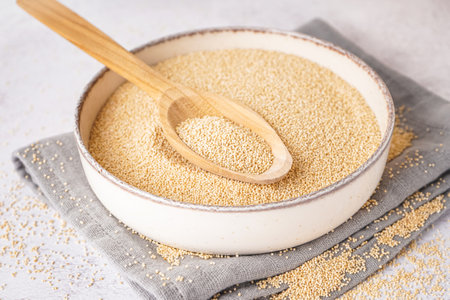 Bowl and spoon of amaranth seeds on light background, closeupの写真素材