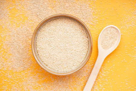 Wooden bowl of amaranth seeds on yellow backgroundの写真素材
