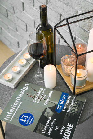 Table with burning candles, wine and magazine in the interior of the roomの写真素材