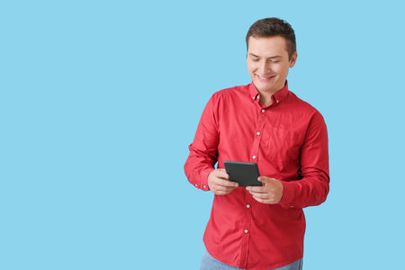 Young man with e-reader on color background