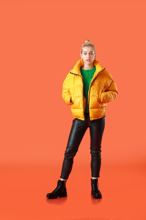 Beautiful young woman in warm clothes on color backgroundの写真素材