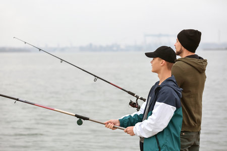 Father and son fishing together on the riverの写真素材