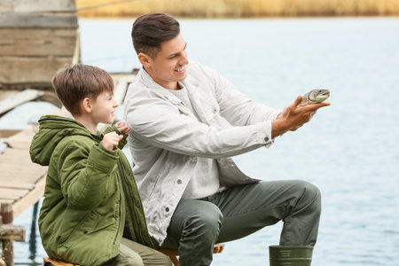 Little boy and his father fishing on the riverの写真素材