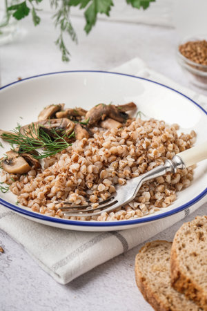 Plate of tasty buckwheat porridge with mushrooms and dill on gray tableの写真素材