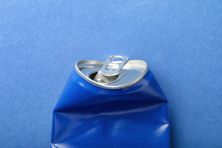 Crumpled can of soda on blue background