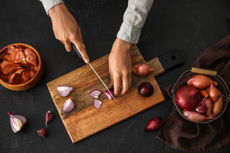 Woman cutting red onion on dark backgroundの写真素材
