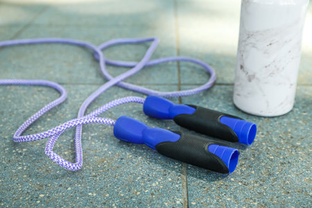 Skipping rope and sports water bottle on tile outdoors, closeupの写真素材