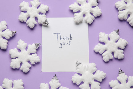 Paper sheet with text THANK YOU and snowflakes on lilac backgroundの写真素材