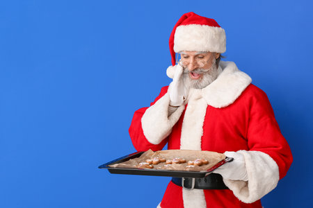 Santa Claus with tasty gingerbread cookies on color backgroundの写真素材