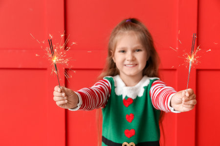 Cute little girl with Christmas sparklers on color backgroundの写真素材