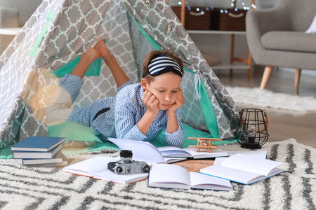 Cute little boy reading book at homeの写真素材