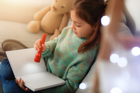 Cute little girl reading book at homeの写真素材