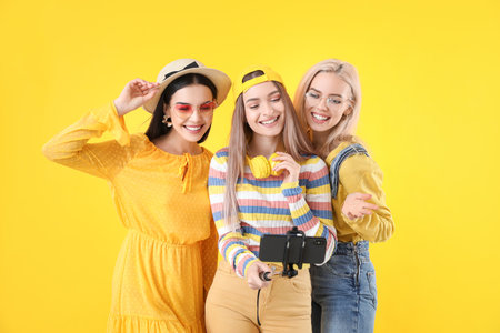 Beautiful young women taking selfie on color background