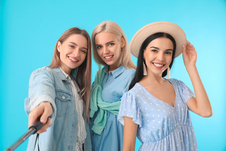 Beautiful young women taking selfie on color backgroundの写真素材