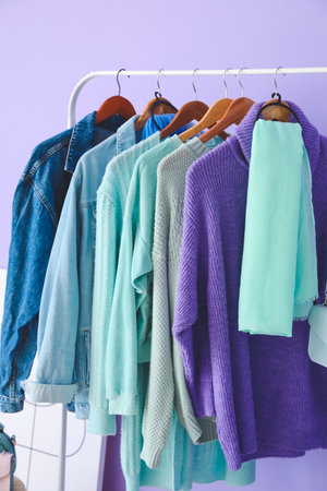 Rack with autumn clothes in interior of modern room