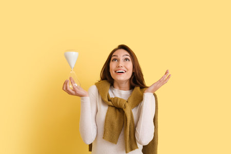 Happy young woman with hourglass on color background