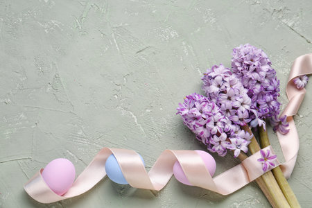 Composition with beautiful hyacinth flowers, ribbon and Easter eggs on grunge background