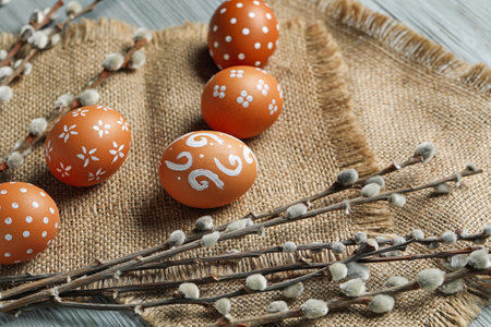 Napkin with painted Easter eggs and willow branches on table, closeup