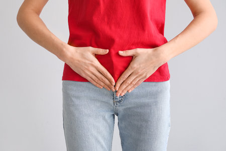 Young woman having menstrual cramps on gray background, closeupの写真素材